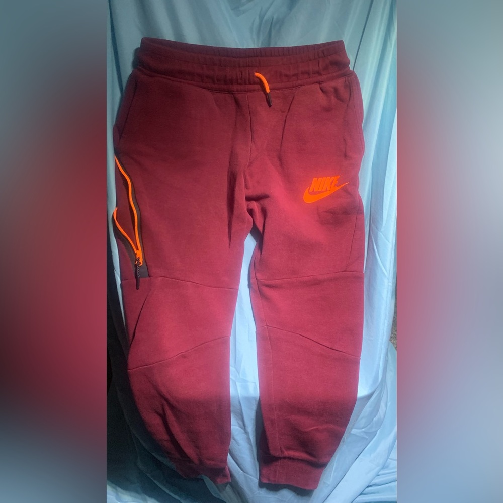 Red Maroon Nike kids sweatpants with orange accents and zipper pockets